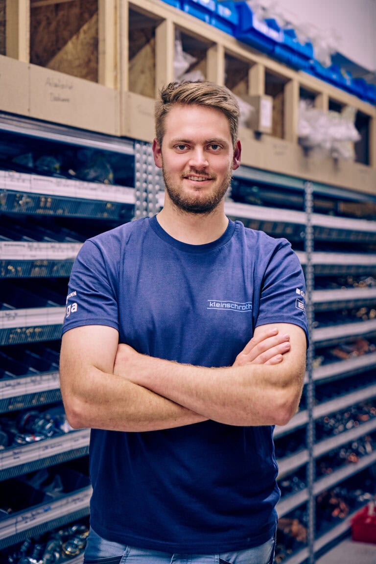 Felix Pletschacher steht mit verschränkten Armen und lächelnd in der Werkstatt von Kleinschroth Wärme.