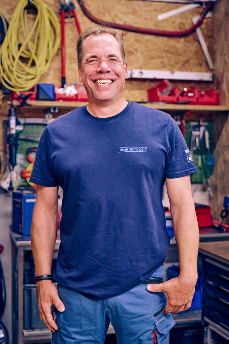 Maler Oliver Burlefinger lächelt mit seinem blauen T-Shirt in die Kamera.