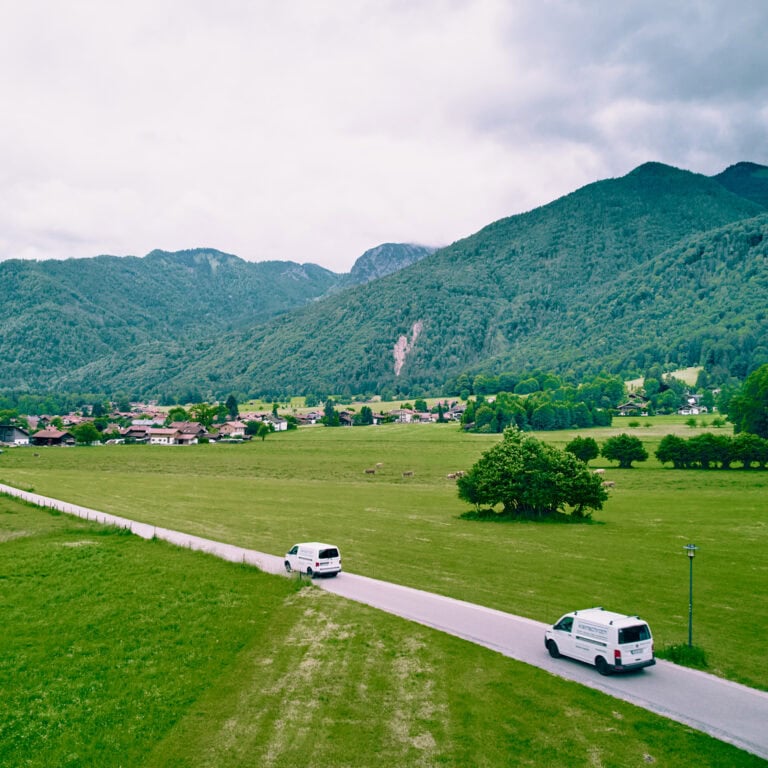Zwei Autos der Firma Kleinschroth fahren an Feldern vorbei Richtung Schleching – zum Einsatz.