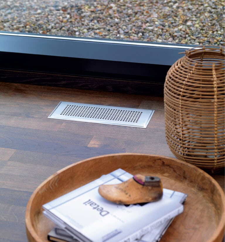 Lüftungssystem im Boden. Holzboden auf dem ein Gitter aus Metall für die Lüftung des Raumes befestigt ist.