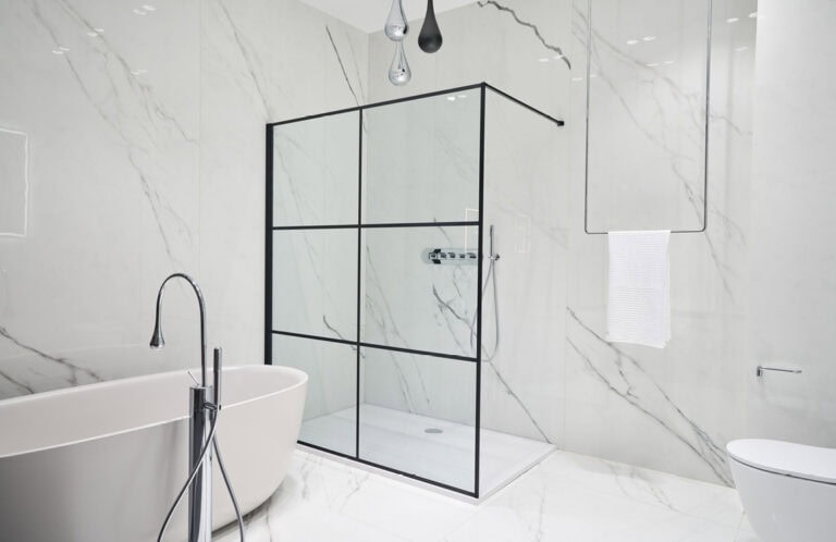 Luxusbad aus Marmor an den Wänden und an dem Boden mit Handtuchhalter der von der Decke kommt und gläserne Duschtrennwand.