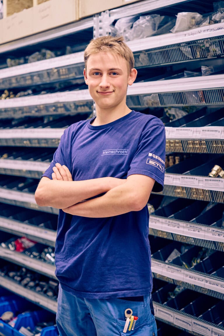 Azubi Tobias Ritzer lächelt mit verschränkten Armen in die Kamera.